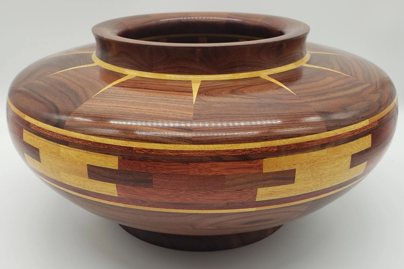 Low wide segmented wooden vessel in rich rosewood tones with pale gold rays at the neck and a stepped gold band around its widest point