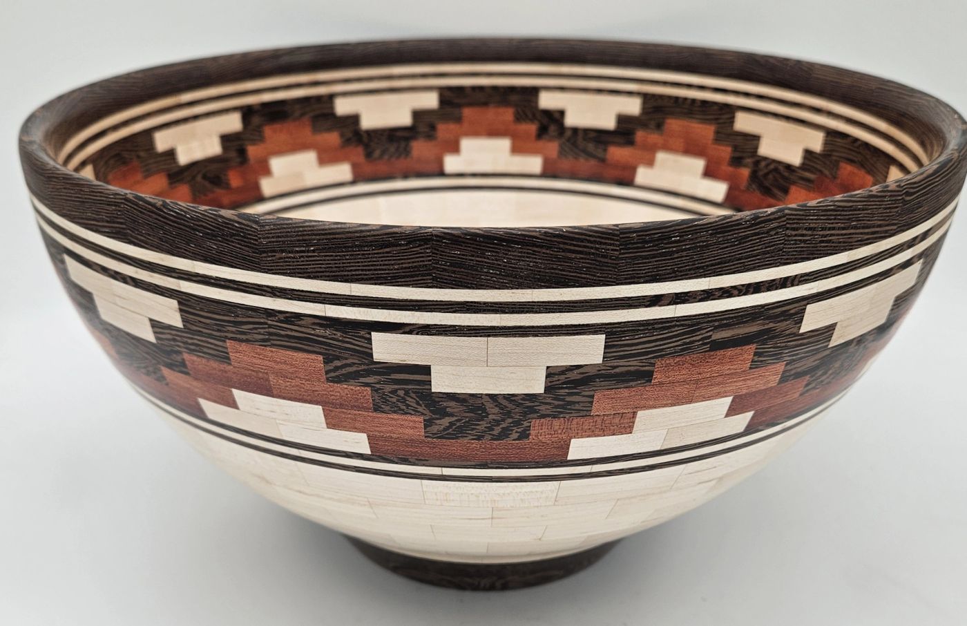 Open segmented wooden bowl in pale maple crossed by two stepped bands in dark brown and russet hardwood